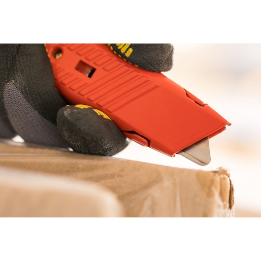 STANLEY 0-10-189 utility knife with red handle cutting cardboard, close-up photography.