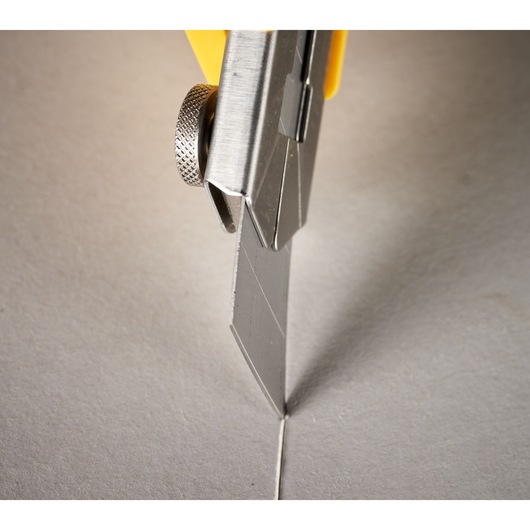 STANLEY 0-11-725 utility knife cutting gray cardboard, close-up photography.