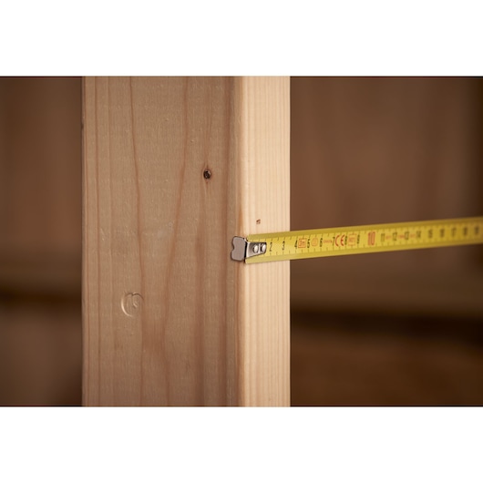 STANLEY 0-32-189 tape measure extended against wooden beam, close-up, product category photography.