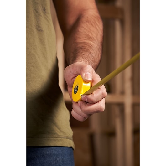Photo of STANLEY 0-32-189 yellow tape measure in use, close-up view of hand holding measuring tape.