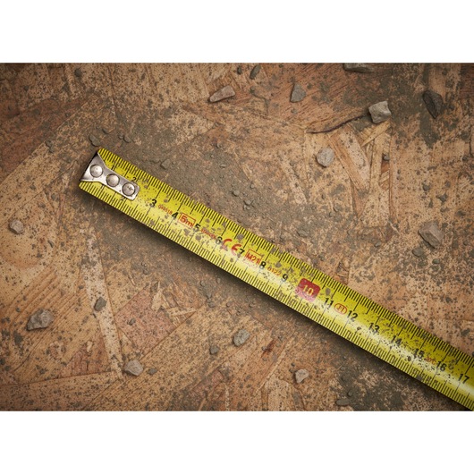 STANLEY 0-33-552 yellow tape measure on rough plywood surface with small stones.