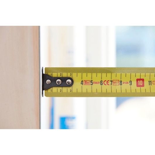 STANLEY 0-33-728 tape measure, yellow, close-up side view showing metric and imperial markings.