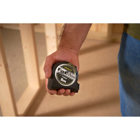 Stanley 0-33-892 FatMax tape measure held in hand, photography, black and yellow design, 8m length.