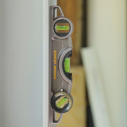 Stanley 0-43-609 photography of multi-angle spirit level tool attached vertically on a white surface.