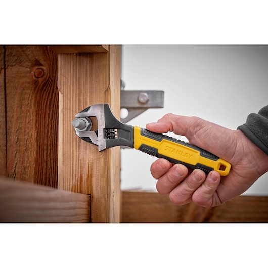 STANLEY 0-90-947 adjustable wrench with yellow and black Control-Grip handle in use tightening a bolt.