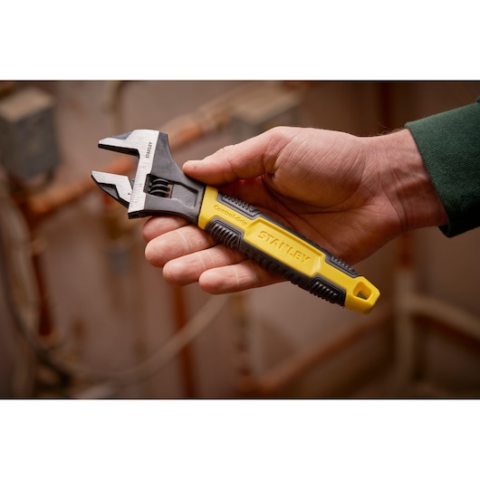 STANLEY 0-90-948 adjustable wrench with yellow and black ControlGrip handle held in a hand.