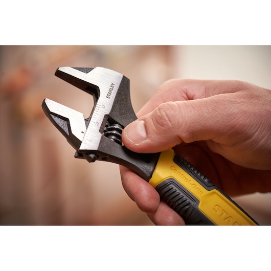 STANLEY 0-90-950 adjustable wrench with yellow and black handle held in hand, close-up.