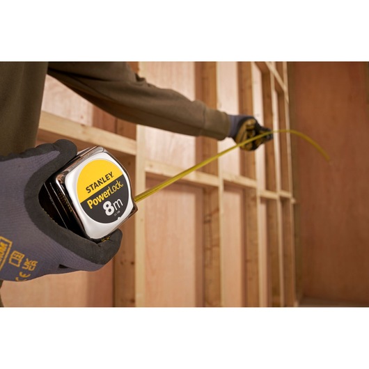 STANLEY 1-33-198 tape measure in use, measuring wooden frame, close-up photography.
