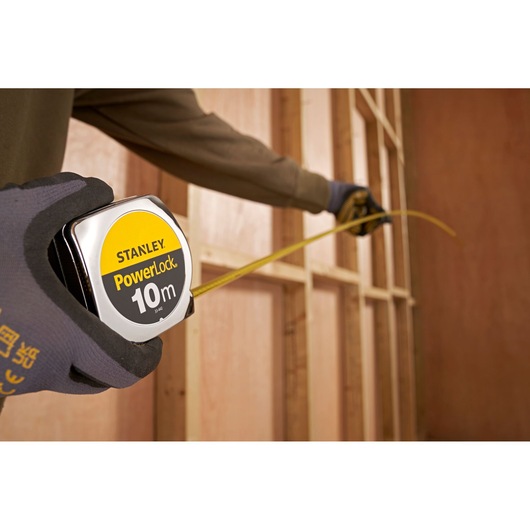 Person using STANLEY 1-33-442 PowerLock 10m tape measure for wood framing measurement.
