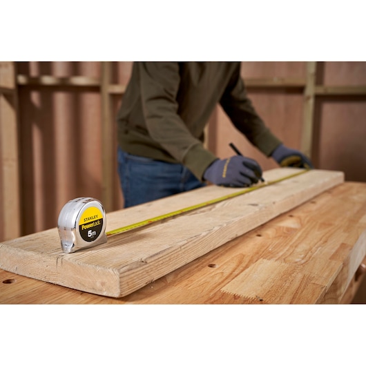 STANLEY 1-33-552 tape measure on wood, worker marks board during carpentry, product photography.