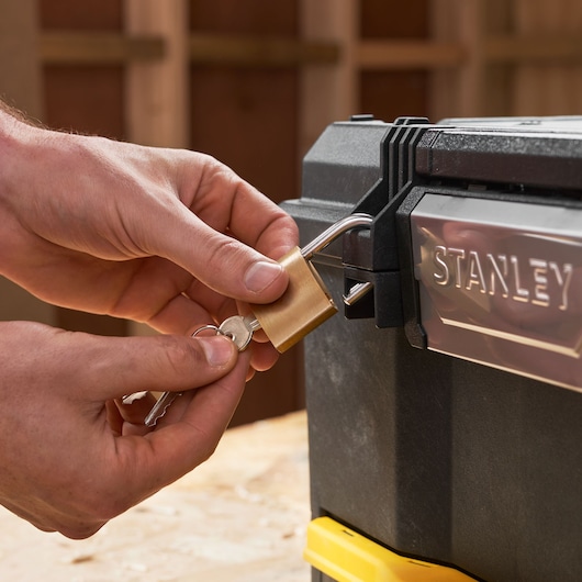 Close-up of STANLEY 1-70-316 toolbox being locked with a brass padlock and keys.