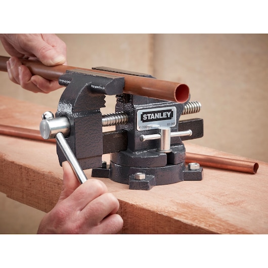 STANLEY 1-83-065 bench vice holding copper pipe on wooden surface, close-up photography.