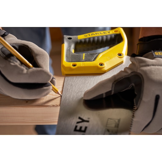 STANLEY 2-15-599 saw in use, gloved hands measuring and marking wood, close-up view.
