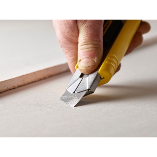 STANLEY 3-11-725 utility knife with yellow handle used to cut drywall, close-up photography.