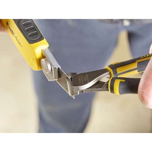 STANLEY 3-11-725 pliers with yellow and black handles cutting metal, close-up photography.