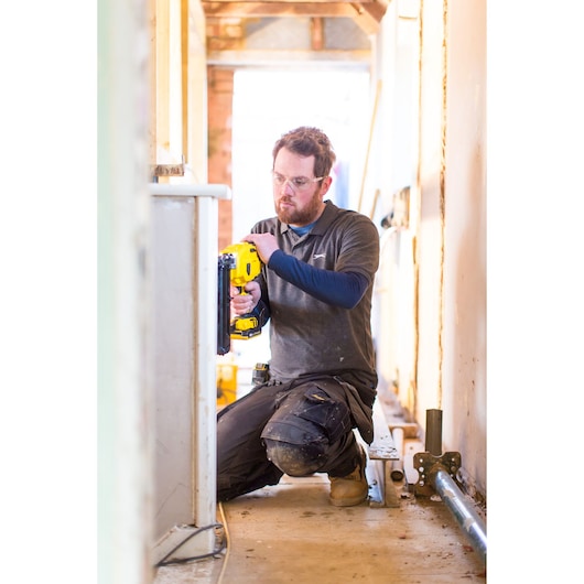STANLEY FMC792B photography showing a worker using a yellow power tool during construction, kneeling indoors.