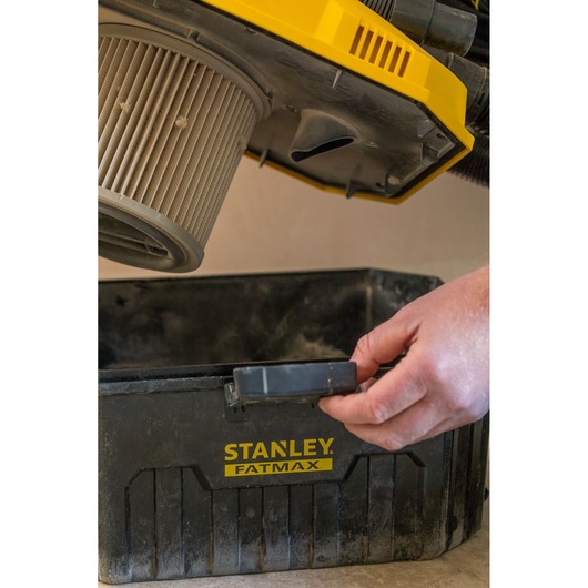 STANLEY FMC795B wet and dry vacuum canister with visible filter, open container and hand unclipping latch.