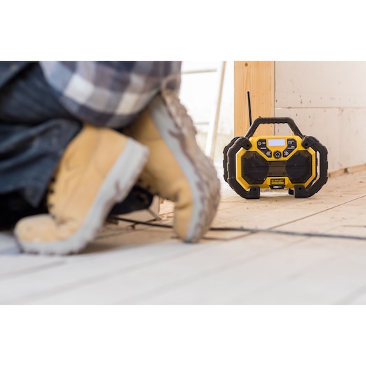 STANLEY FMCR001B jobsite radio yellow and black on construction floor near worker boots.