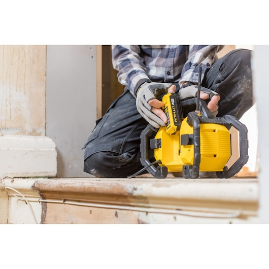 STANLEY FMCR001B jobsite radio with battery, yellow-black, in use during indoor renovation.