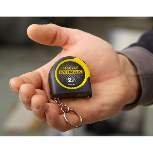 STANLEY FMHT0-33856 FATMAX 2m tape measure keychain held in hand, black and yellow compact design.