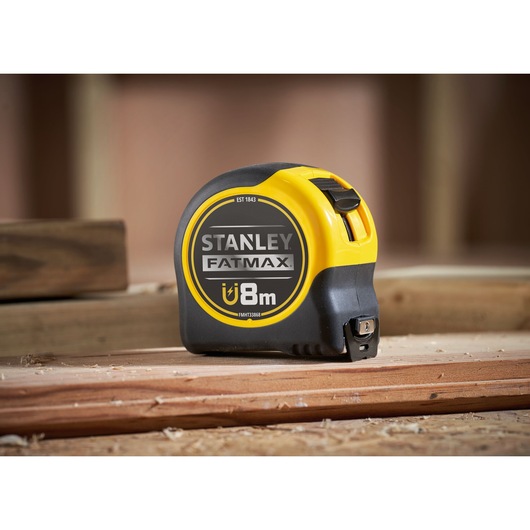 STANLEY FMHT0-33868 FATMAX magnetic tape measure, 8m, black and yellow, side view, on wood surface.