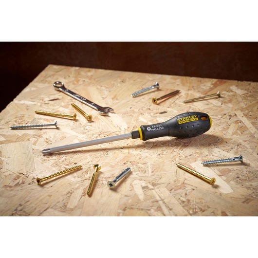 STANLEY FMHT0-62623 screwdriver with black and yellow handle on wood surface surrounded by screws and a wrench.