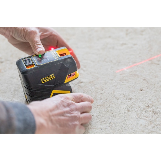 Photo of STANLEY FMHT1-77415 laser level on floor in use, projecting red laser line.