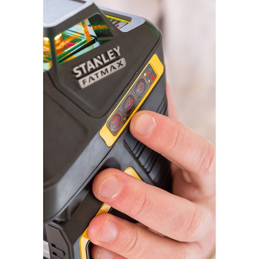 STANLEY FMHT1-77416 laser level close-up with hand pressing control buttons, product photography.