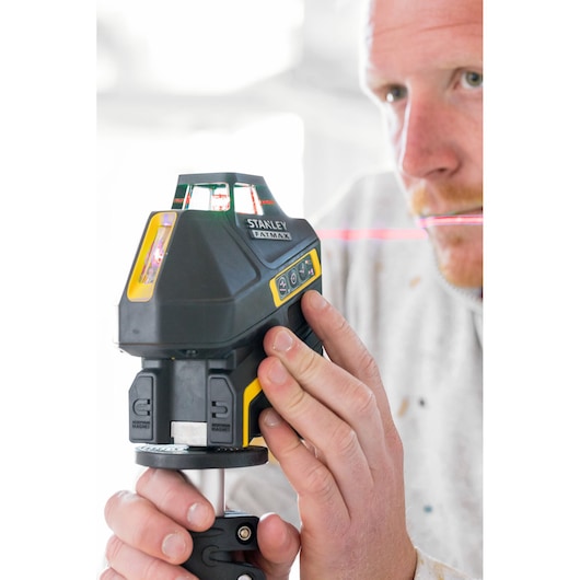 Photo of STANLEY FMHT1-77416 laser level on tripod, person adjusting controls, visible red laser line.