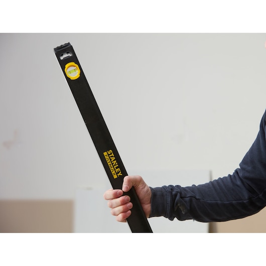 Photo of STANLEY FMHT42447-1 black level tool held in hand, showing yellow bubble vial and brand logo.