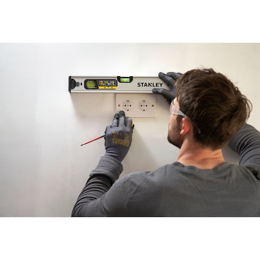 STANLEY FMHT43670-1 spirit level used by a person marking wall above electrical sockets, angled top view.