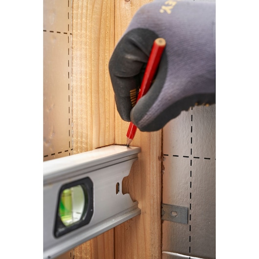 STANLEY FMHT43671-1 spirit level held against wood, gloved hand marking with red pencil, side view.