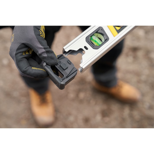 STANLEY FMHT43674-1 level accessory in hand, close-up photo with gloves outdoors.