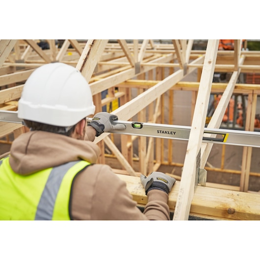 Photo of worker using STANLEY FMHT43680-1 spirit level on wooden frame at construction site.