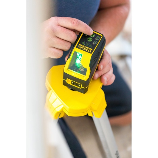STANLEY FMHT77586-1 laser level on tripod, close-up of hand adjusting controls.