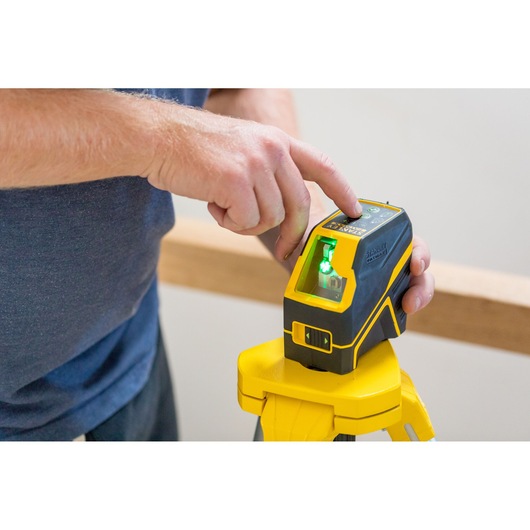 STANLEY FMHT77595-1 laser level device with green light on tripod, operated by hand.
