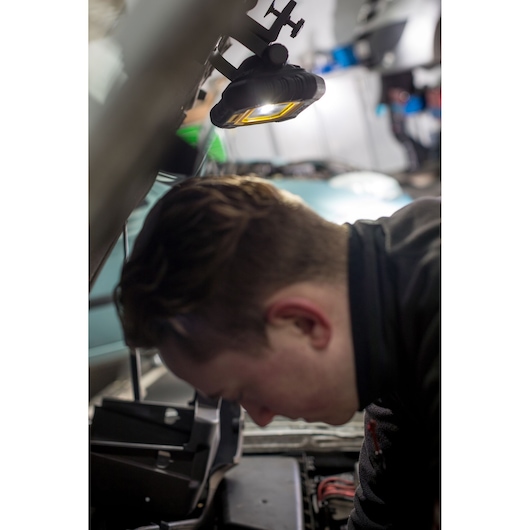 STANLEY FMHT81507-1 work light clamped to car hood, illuminating engine bay during automotive repair.