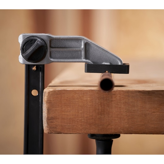 STANLEY FMHT83006-0 clamp holding a metal pipe on a wooden workbench, side angle photography.