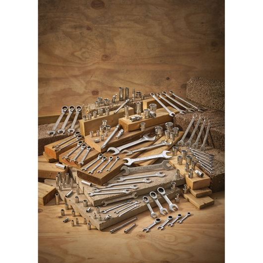 A collection of metal wrenches and sockets arranged on wooden blocks, displayed against a wooden background.