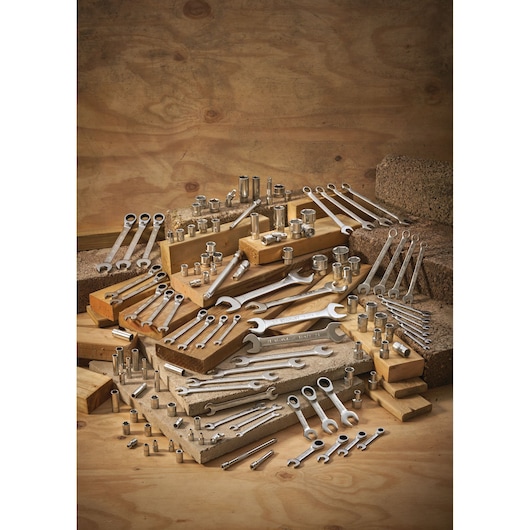 Assorted spanners and sockets are arranged on wooden blocks for display against a wood background.