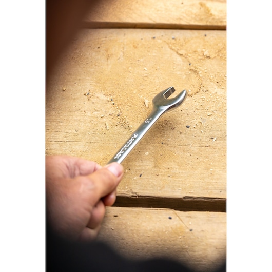 STANLEY FMMT13062-0 open end wrench held by hand on wooden surface, product photography.