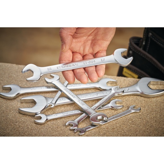 STANLEY FMMT13067-0 spanner set, silver wrenches on workbench, hand holding one wrench, product photography.