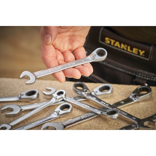 STANLEY FMMT13088-0 photography of a hand holding a combination wrench above several wrenches on a work surface.