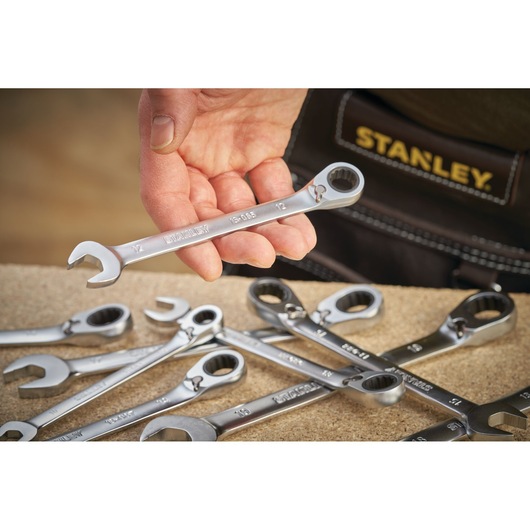 Photo of STANLEY FMMT13095-0 ratcheting combination wrench held by hand, with other wrenches on a workbench.