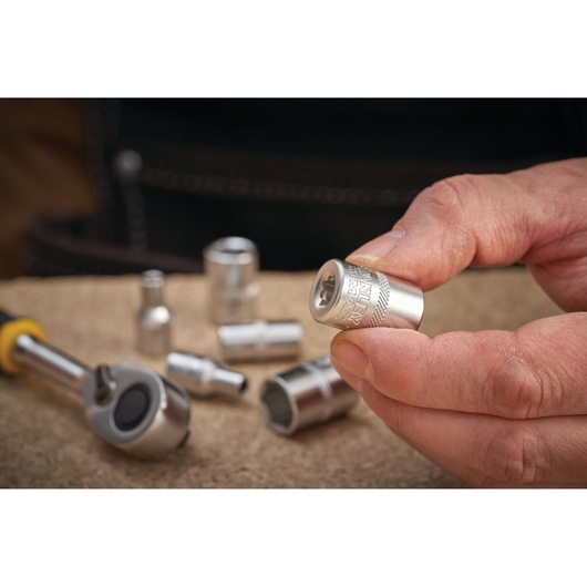 STANLEY FMMT17192-0 chrome socket held in hand with ratchet and sockets on workbench.