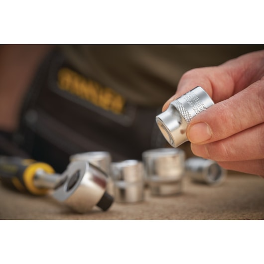 Photo of STANLEY FMMT17218-0 socket held by hand with other sockets and ratchet tool in background.
