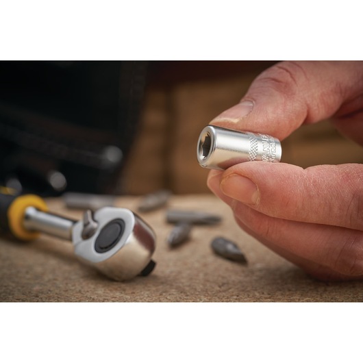 STANLEY FMMT18007-0 socket tool held by hand, with ratchet and bits on tabletop, close-up photo.
