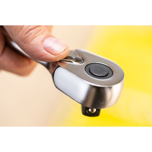 Photo of a STANLEY FMMT82680-0 ratchet handle, close-up showing thumb pressing quick-release button.