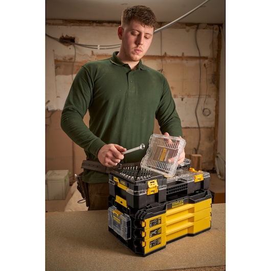 Photo of STANLEY FMMT98104-0 stackable toolboxes with clear lids and yellow accents on a workbench.