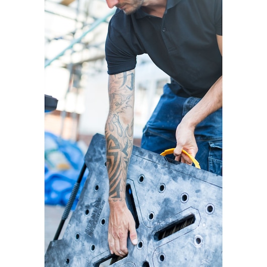 Photo of person carrying STANLEY FMST1-75672 black folding workbench by yellow handle.